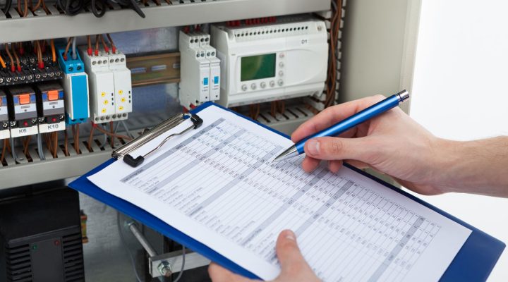 An electrician documents findings on a clipboard while conducting an electrical inspection.
