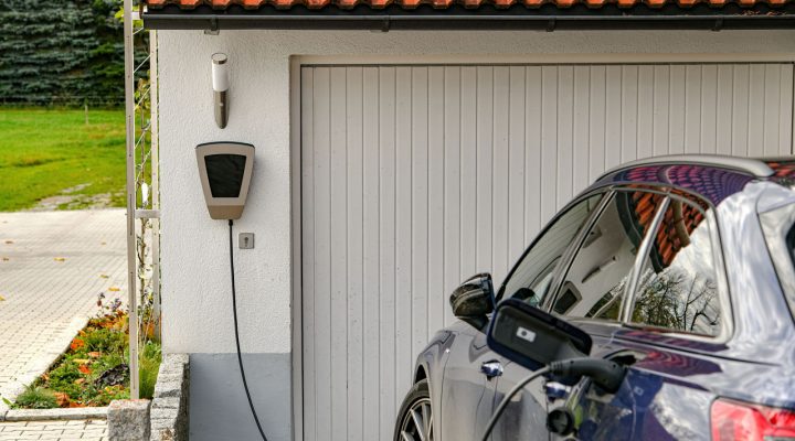 An electric vehicle plugged into a wall-mounted EV charger, showcasing sustainable energy solutions.
