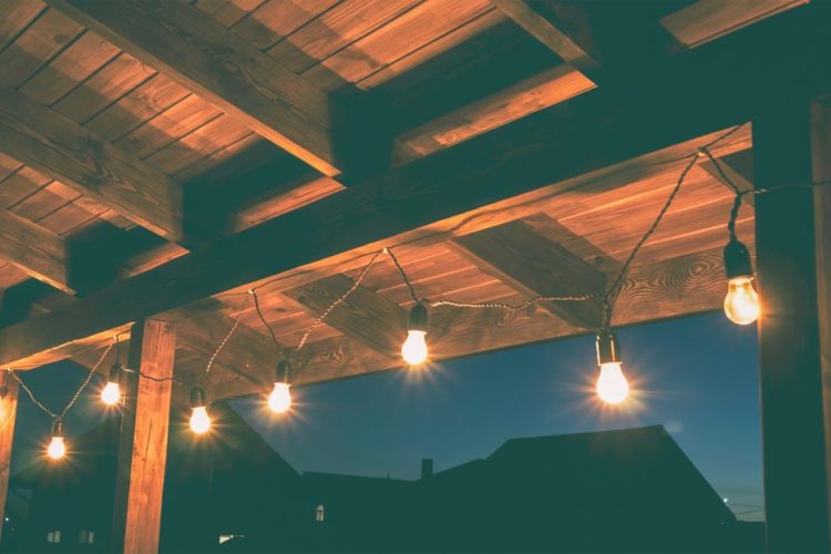 Warm string lights hanging from a wooden patio ceiling, creating a cozy and inviting outdoor ambiance.