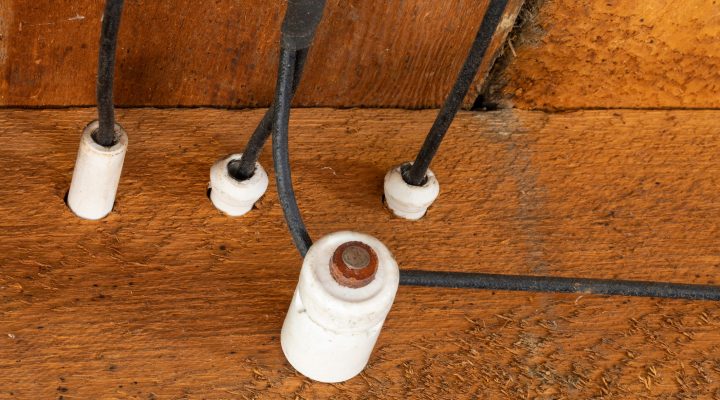 Vintage knob-and-tube wiring installed in a wooden structure, showcasing older electrical systems.