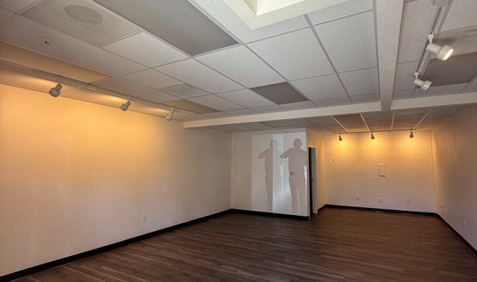 A newly renovated commercial office space in San Diego featuring new wood-look flooring and a complete lighting upgrade with modern track lights installed by Mizo Electric, creating a bright and professional environment.