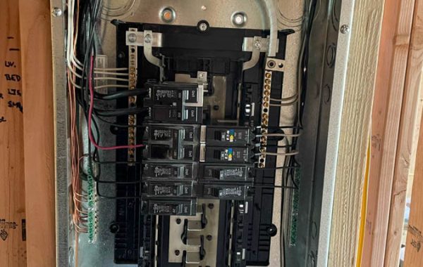 A detailed view of an electrical panel being installed during construction, showcasing organized wiring and components.