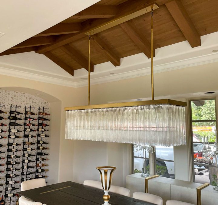 A luxurious dining room featuring a sophisticated chandelier and wall-mounted wine rack, blending style and functionality.