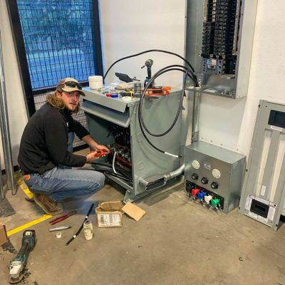 A professional electrician works on industrial equipment, demonstrating expertise in complex electrical systems.