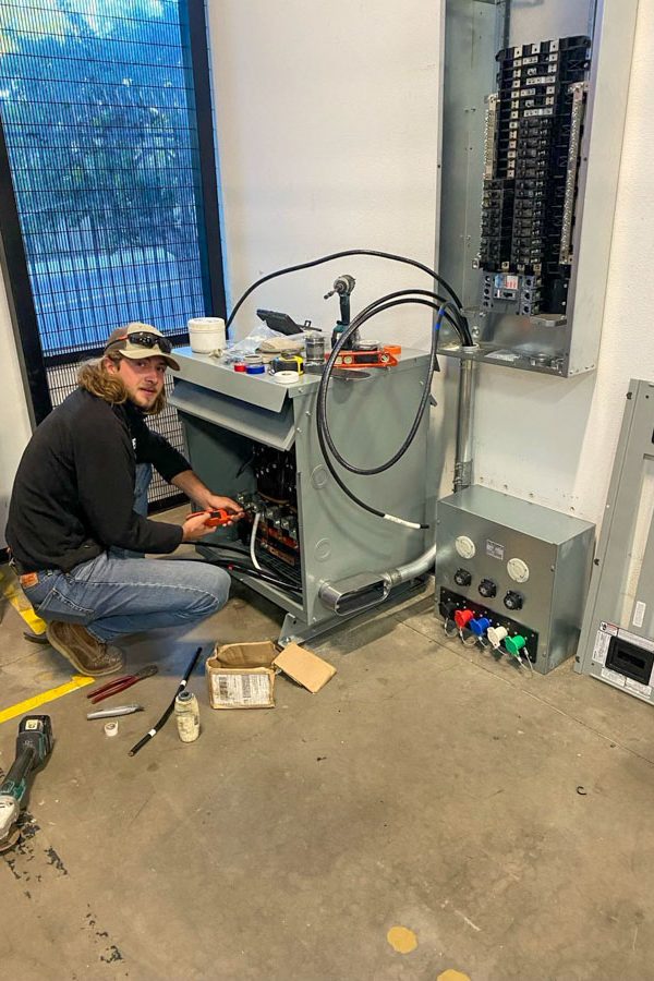 A professional electrician works on industrial equipment, demonstrating expertise in complex electrical systems.