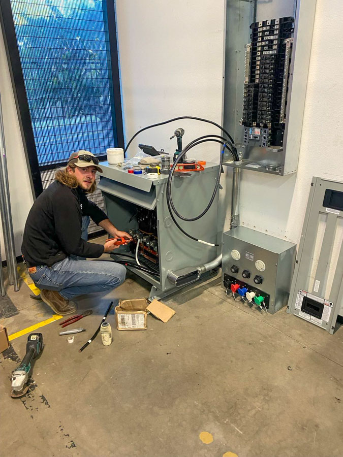 A professional electrician works on industrial equipment, demonstrating expertise in complex electrical systems.