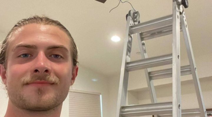 An electrician prepares to install or repair a ceiling fan, showcasing expertise in home electrical work.