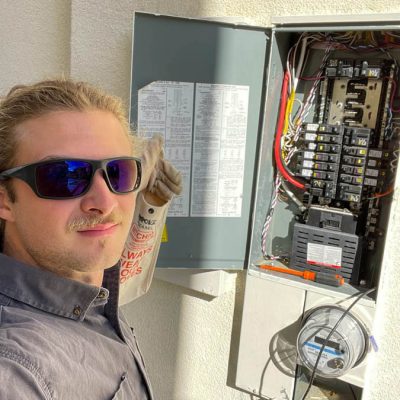 An electrician wearing gloves and safety gear inspects an electrical panel, ensuring safe and reliable power distribution.