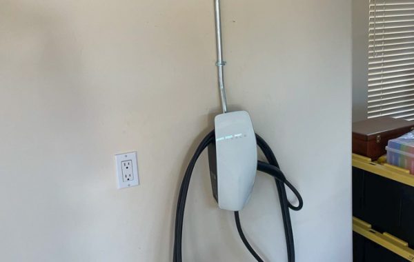 A sleek Tesla electric vehicle charger mounted on a wall, providing efficient and eco-friendly charging options.