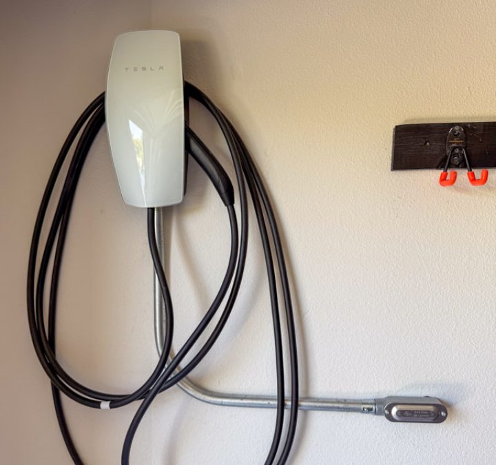 A close-up view of a flawlessly installed Tesla Wall Connector, showcasing the neat metal conduit and professional finish that Mizo Electric delivers on every residential EV charging station project in North County.