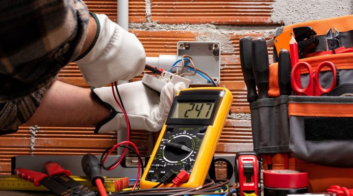An electrician uses a multimeter to test voltage levels during an inspection.